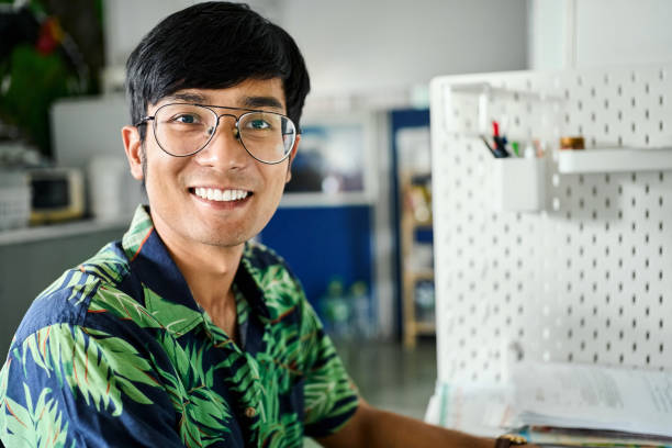 istock Smiling young man in hawaiian shirt working at small office 2159896376