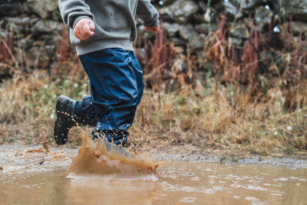 istock A young boy is running through a puddle of water 2159898461