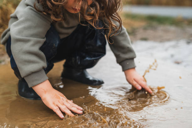 istock A child is playing in the rain, splashing water with their hands 2159898509