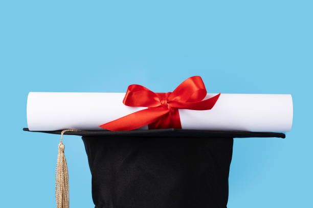 istock Graduation cap and diploma on blue background, education and intelligence, academic accomplishment celebration 2159900440