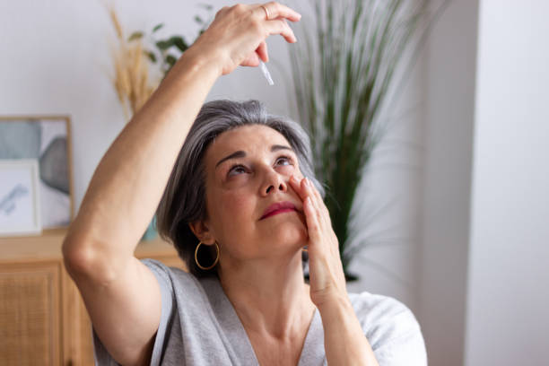 Senior woman applying eye drops suffering from cataract and glaucoma
