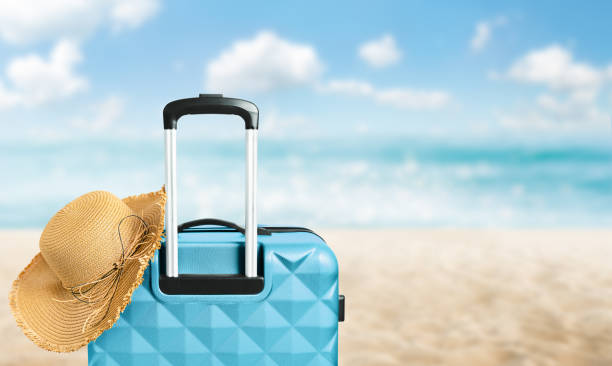 istock suitcase and sun hat on the beach 2159900849