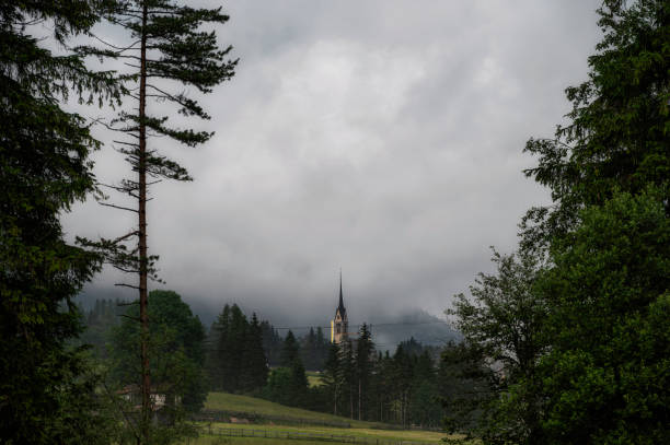 alpine landscape with a clouds partially covering the mountains  inside Val di fassa, Dolomites, Italy