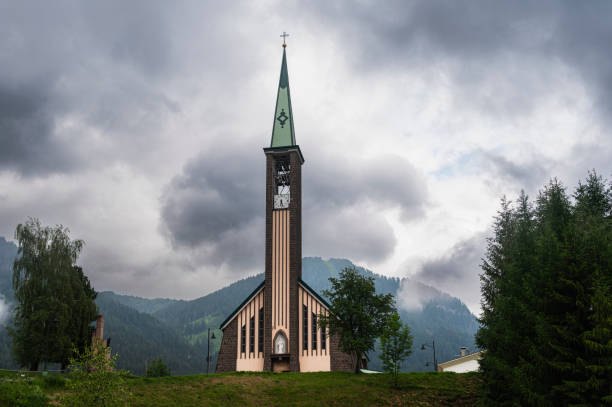 church in Pozza di Fassa with a cloudy sky in the background, Val di Fassa, Italy