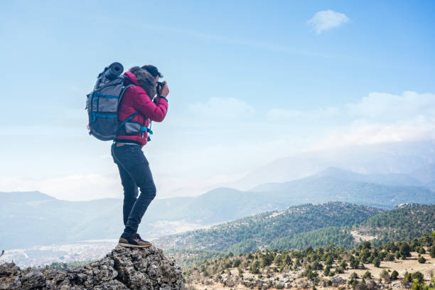 istock Photographer on mountain top taking photos over clouds. 2159902966