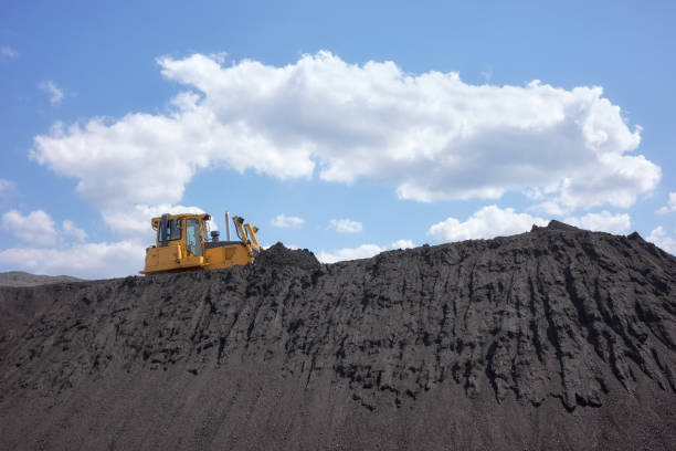 A bulldozer on a coal heap against the sky.