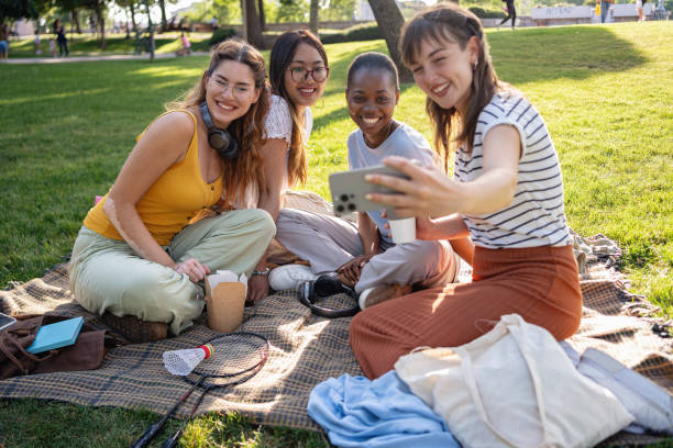 istock Group of multiracial female university students taking selfie with mobile phone while enjoying the picnic at the campus park 2159914372