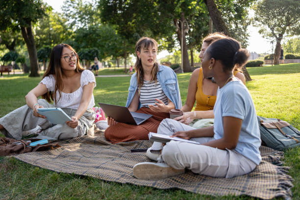 istock Group of multiracial female university students spending day in campus park while studying together 2159914381