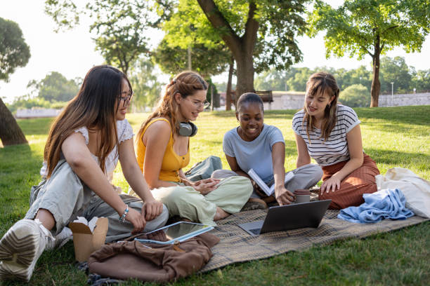 istock A group of multiracial female university students have fun in a campus park while studying together 2159914383