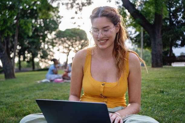 istock Young female Caucasian University student with vitiligo studying on a laptop while sitting on the grass in a campus park 2159914459