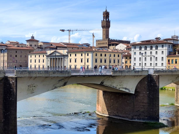 Tourists walking on the Ponte alle Grazie, a bridge crossing the Arno river in Florence historical centre, Tuscany, Italy.
