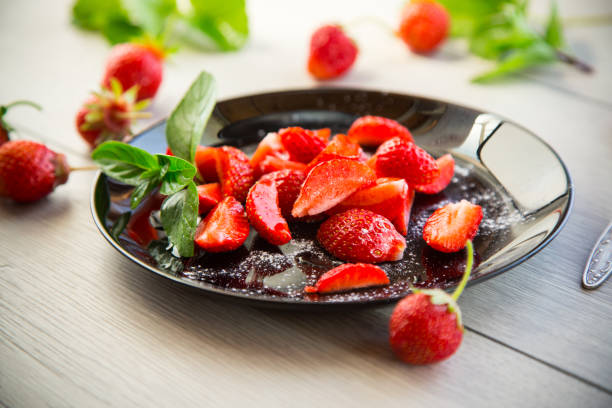 fresh fruit salad of ripe strawberries on a light wooden table