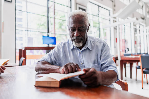 Senior man reading a book at library
