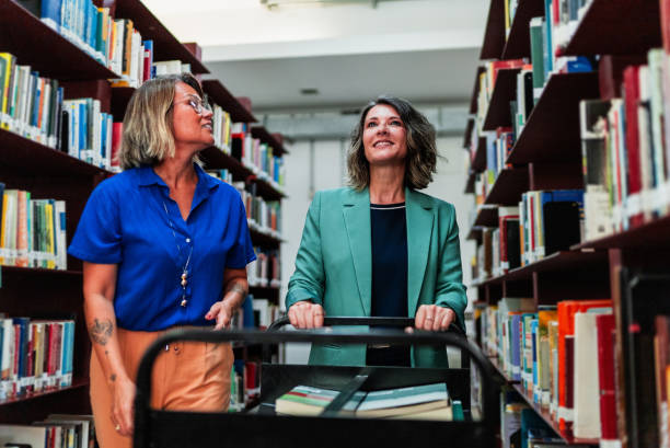istock Mature librarians talking and organizing the library 2159920064
