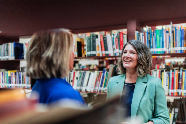 istock Mature women talking at library 2159920079