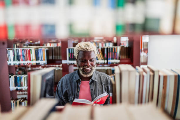 istock Mid adult man looking for a book in the library 2159922621