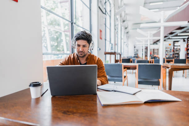 istock Mid adult man working using laptop at library 2159922632