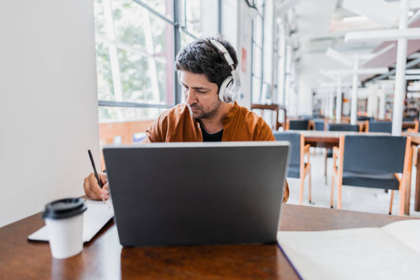 Mid adult man working using laptop at library