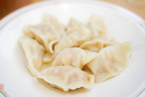 Wrapped dumplings are neatly arranged on the chopping board during winter shooting.Dumplings are a kind of food from China that is stuffed with dough and shaped like a half-moon or ingot. It is commonly found in China and other parts of East Asia. Dumplings are also an important food on festivals such as the Lunar New Year and the winter solstice. They are also one of the main foods eaten throughout the year in the northern provinces of China.