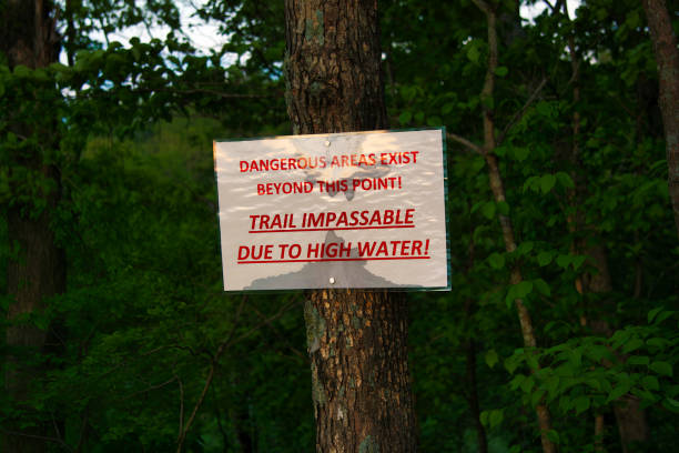 istock Warning sign on tree alerts hikers to dangerous, impassable trail, high water 2159931094