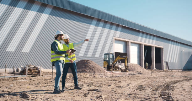 istock Construction, engineering and team planning with tablet outdoor for building inspection or maintenance. Engineer men with technology talking architecture space, project management or site safety 2159933110