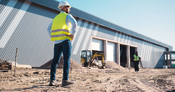 istock Construction, infrastructure and man in site for planning, maintenance and architecture design. Thinking, civil engineering and back of contractor for manufacturing, storage warehouse and factory 2159933113