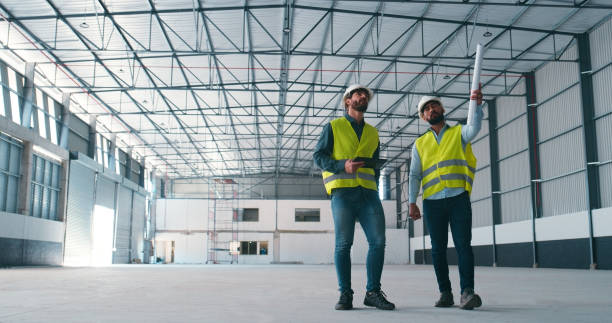 istock Construction, teamwork and men in building for planning, maintenance and inspection for storage. Civil engineering, discussion and contractors with blueprint for manufacturing, warehouse and factory 2159933201