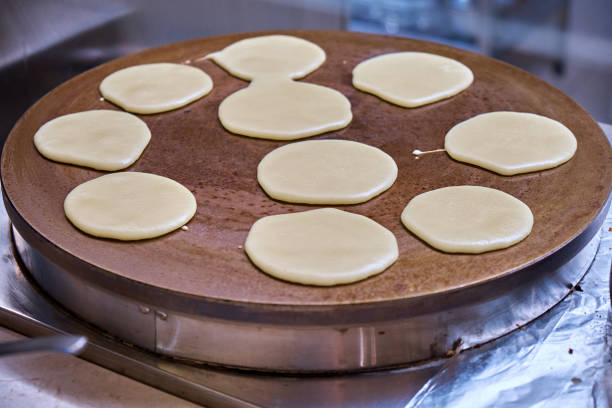 Simultaneous preparation of several pancakes in a large round pan.