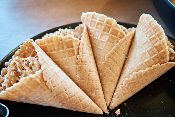 Dessert. Waffle cones filled with cream with nuts on a black plate. Sweet menu Dessert. Waffle cones filled with cream with nuts on a black plate. ice cream with wafer rolls stock pictures, royalty-free photos & images