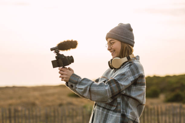 istock Happy lady recording vlog on camera under sundown sky 2159940046