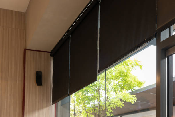 A window with black blinds and a tree outside