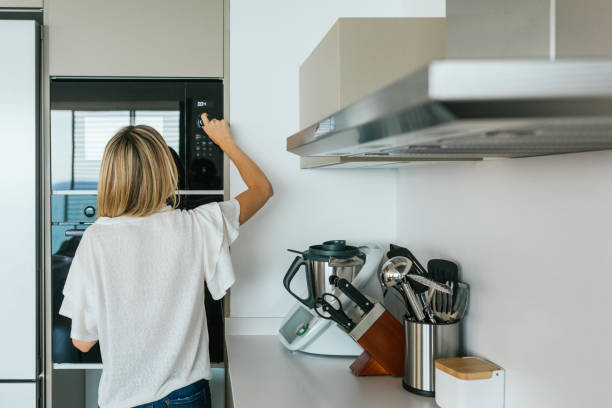 istock Woman turning on microwave oven 2159950183