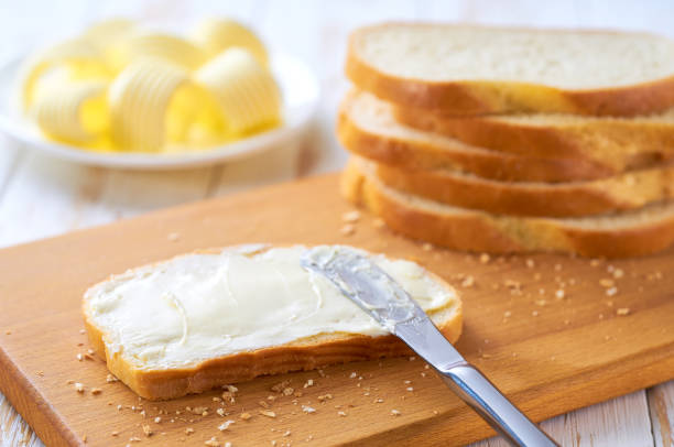 istock Tasty cut wheat bread  with fresh butter on a white wooden table. 2159951630
