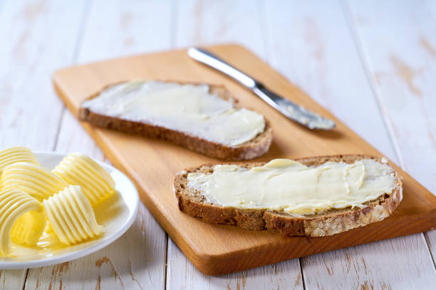 istock knife spreading butter on rye bread slices on a white wooden table. 2159951653