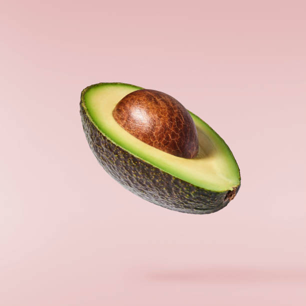 Fresh ripe avocado falling in the air isolated