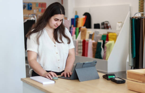 istock Young woman using a tablet in a tailor shop 2159953908