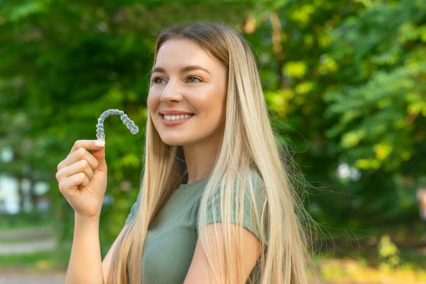 istock Smiling woman with perfect and healthy teeth using removable braces or aligner for straightening and whitening teeth. Orthodontic treatment for correction of bite. 2159954101