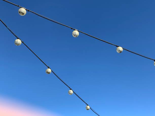 istock Two string lights overhead with clear blue sky in background 2159954673