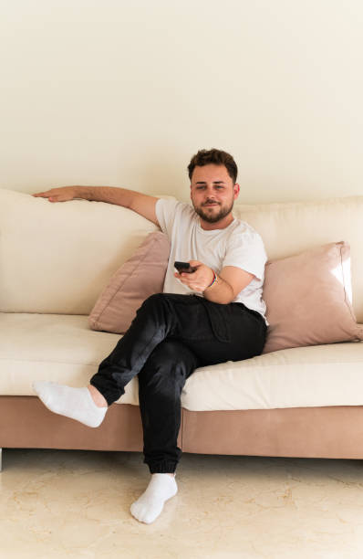 istock Young man relaxing on sofa watching tv 2159958705