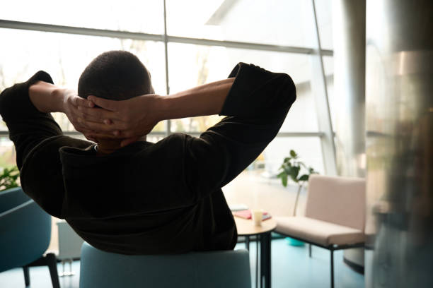 istock Man sitting on chair while holding hands behind head 2159961687
