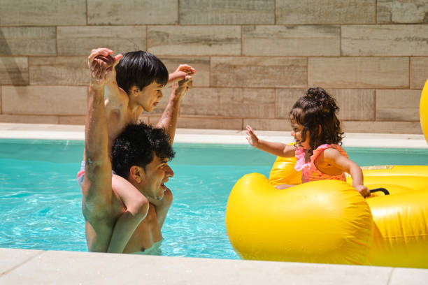 istock A man with his son on his shoulders looking at his daughter in a pool 2159967590