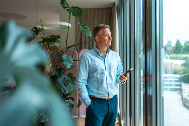 istock Mid Adult Businessman Using Smartphone by Office Window 2159972029