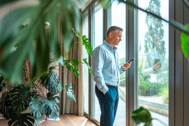 istock Business Professional Engaged with Smartphone by Office Window 2159972052