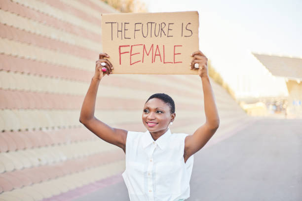 Black feminist woman protesting for equality and women's rights. Holds a sign saying the future is female. Vertical photo