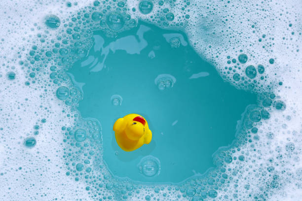 Yellow rubber duck in water with soap foam