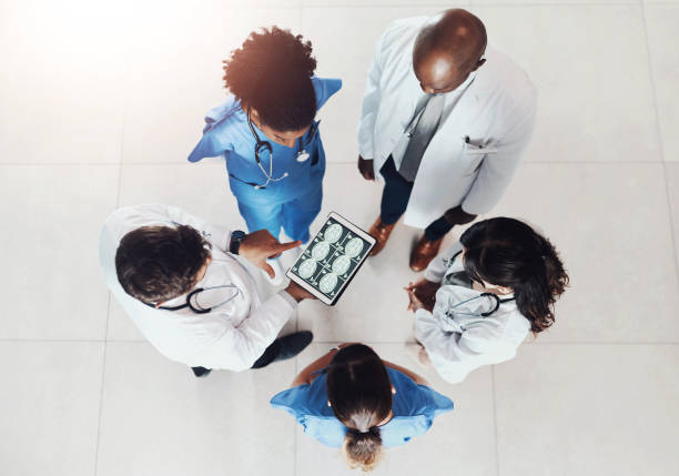 istock Top view, doctors and nurses with tablet screen, x ray and cooperation with cure, results or advice. Group, employees or medical with professional, brain scan or coaching with diagnosis or healthcare 2159986697