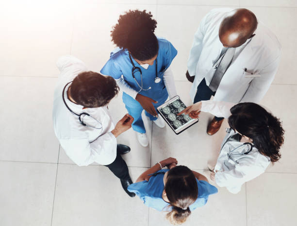 istock Top view, doctors and teamwork with tablet screen, x ray and cooperation with healthcare, help and advice. Group, meeting and medical with brain surgery, tech and people with diagnosis and results 2159986699