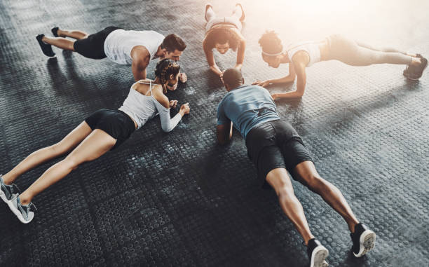istock Class, training and plank in group at gym for workout, core exercise or fitness together indoors. Diverse people, friends and warm up for ab muscle, session and sport for health on gymnasium floor 2159988778