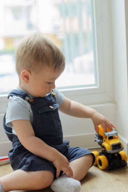 istock A small child plays with a toy car while sitting by the window 2159990600