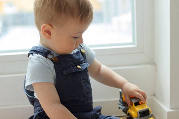istock A small child plays with a toy car while sitting by the window 2159990606